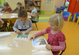 Dwie dziewczynki siedzą przy stole, układają obrazek z części